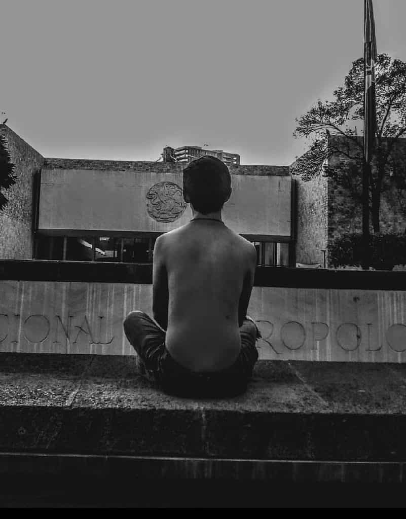 Gay Mexican young Man sitting shirtless outside the National Anthropology Museum.